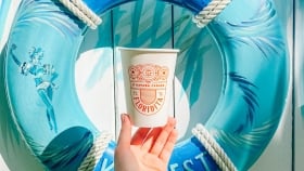 A hand holding a disposable Havana Cabana Floridita cup against a wooden wall background with an inflatable ring