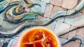 Top shot of a glass of ice-coffee against a ground artwork