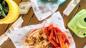 A top shot crispy quesadilla with a side of sweet potato fries next to an instax camera, cutleries