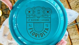 A low angle shot of the Havana Cabana Floridita logo on a plate raised by a pair of hands