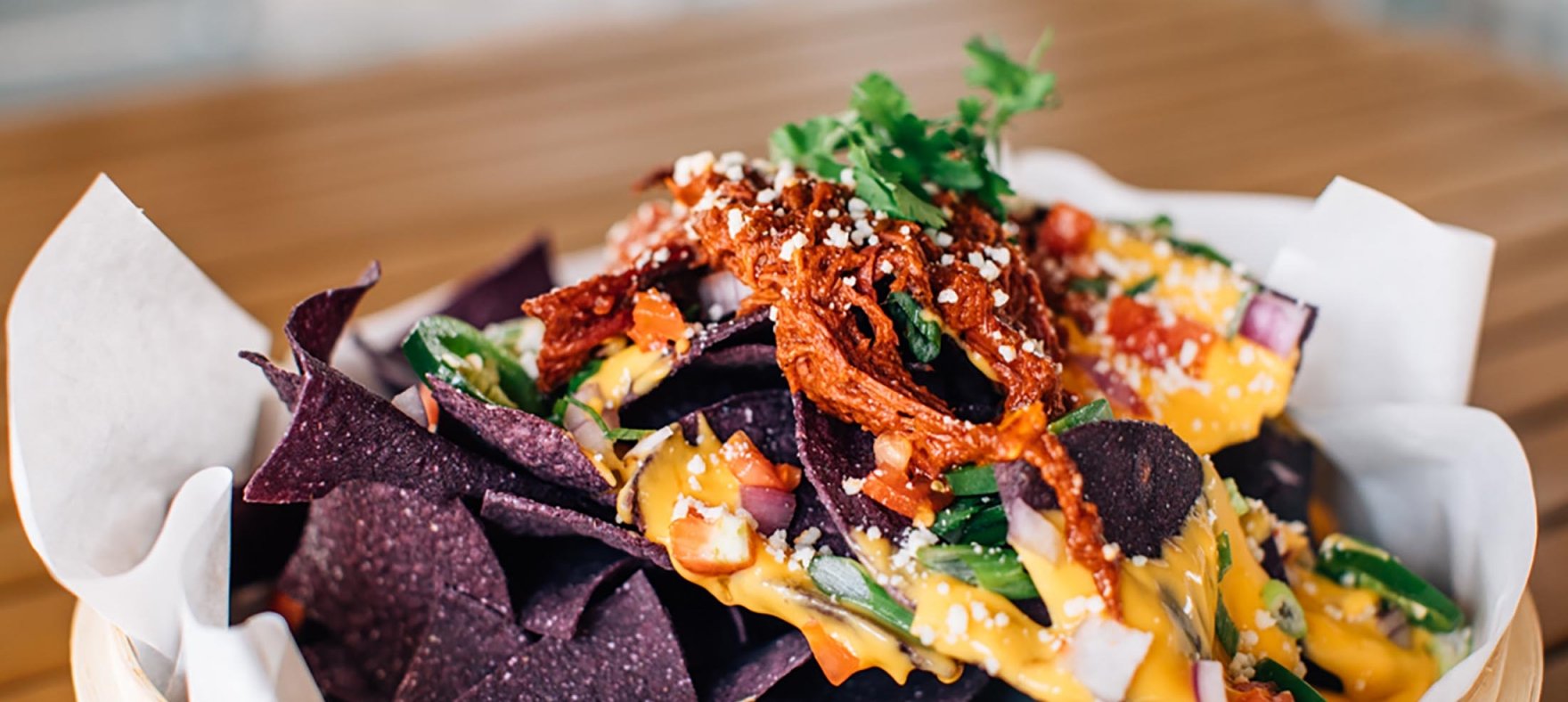 A close up of nachos with blue corn tortilla chips