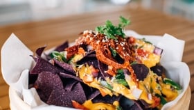 A close up of nachos with blue corn tortilla chips
