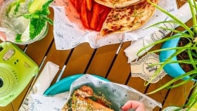 A female hand holding the tortilla from the plate opposite to the quesadilla dish