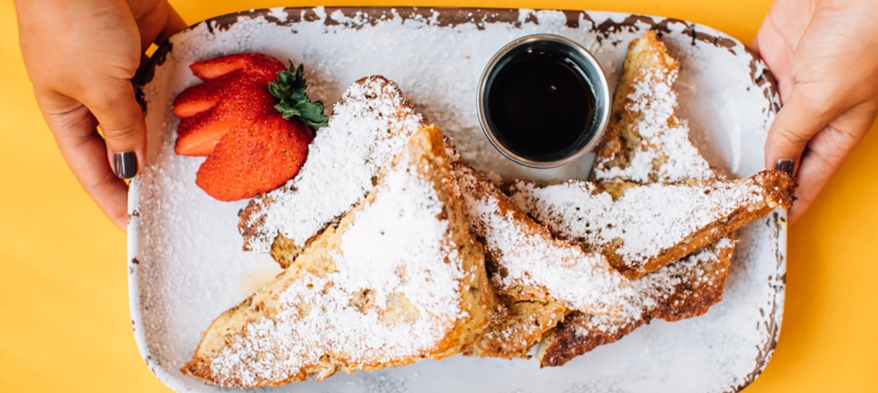 Sugar-dusted french toasts served with honey and slice strawberries