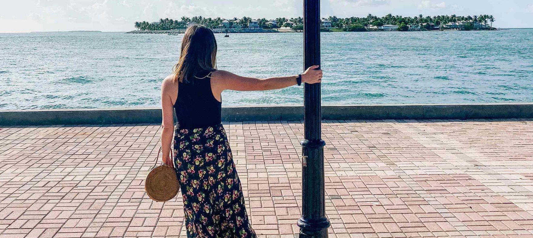 A lady holds on to a lamp post on a boardwalk in Key West, Florida.