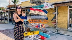 A lady poses next to signpost in Key West, Florida.