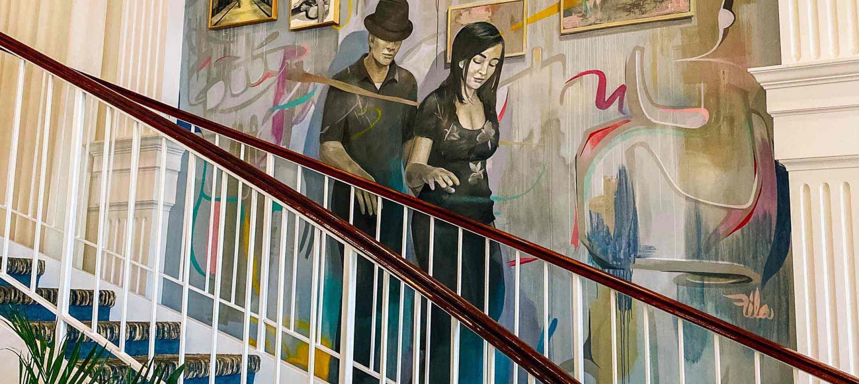 A staircase next to the wall mural with framed artwork and photographs