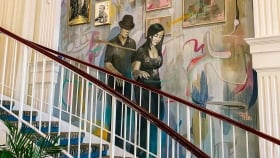 A staircase next to the wall mural with framed artwork and photographs