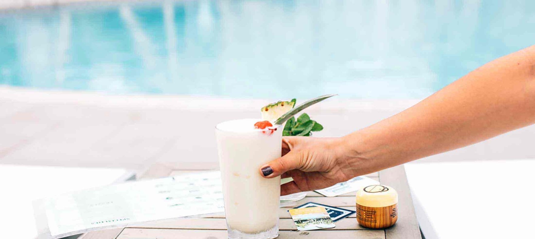 A Piña Colada being served on a poolside table.