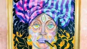 a close focus on the art of a woman wearing a patterned head wrap showcasing her flowing curls