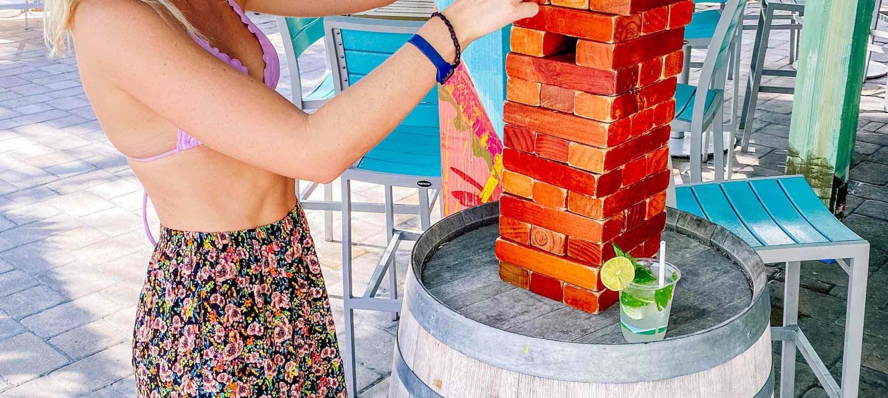 A vertical shot of a woman building a structure with mini bricks on top of a wooden barrel
