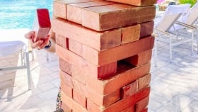 A close up of the mini brick structure with a woman holding a brick in the back