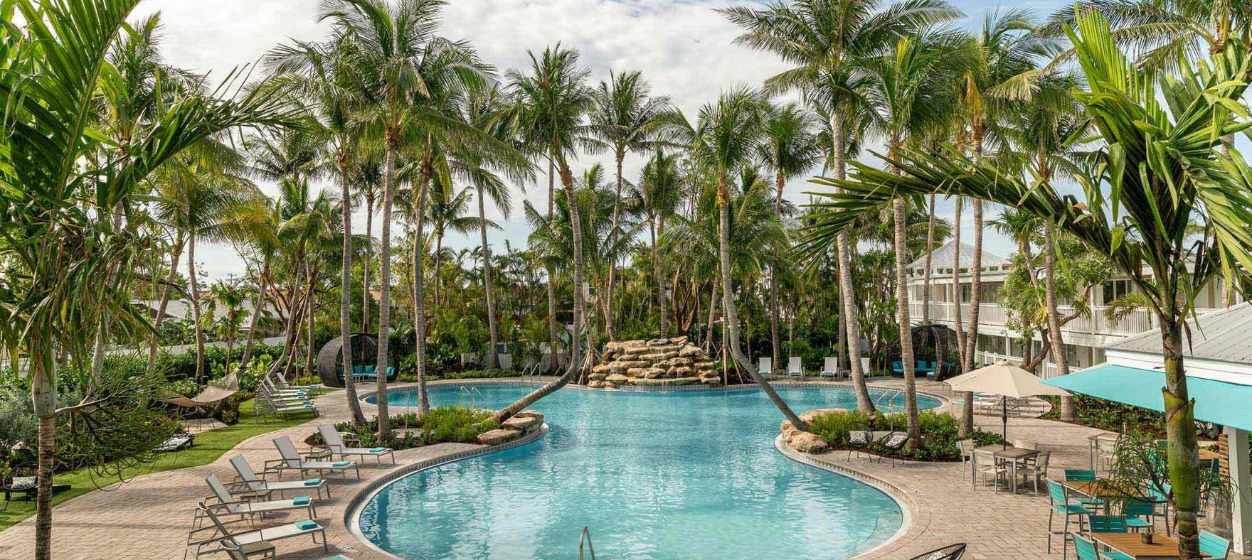 A long shot of the figure-eight swimming pool surrounded by palm trees