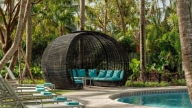 Lined lounge chairs next to the woven gazebo overlooking the pool