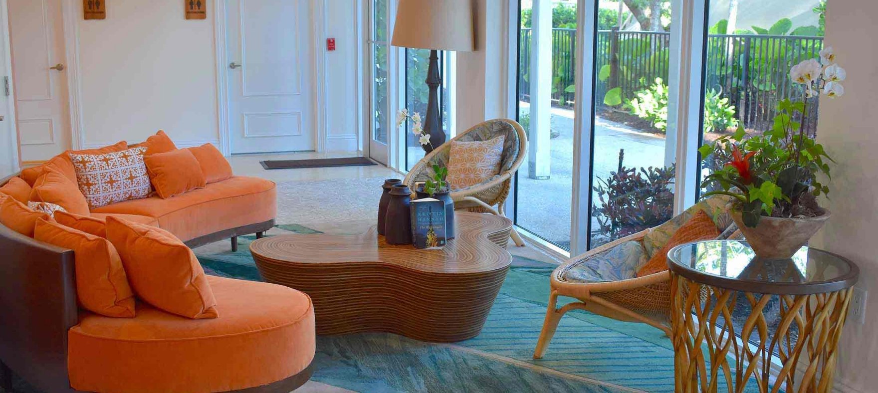 A close-up of a curved sofa next to a pair of woven hoop chairs and a coffee table in the center