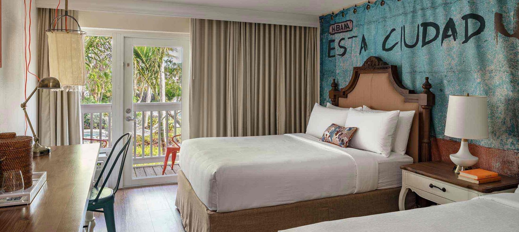Twin queen-sized beds with a bedside table in between overlooking a desk