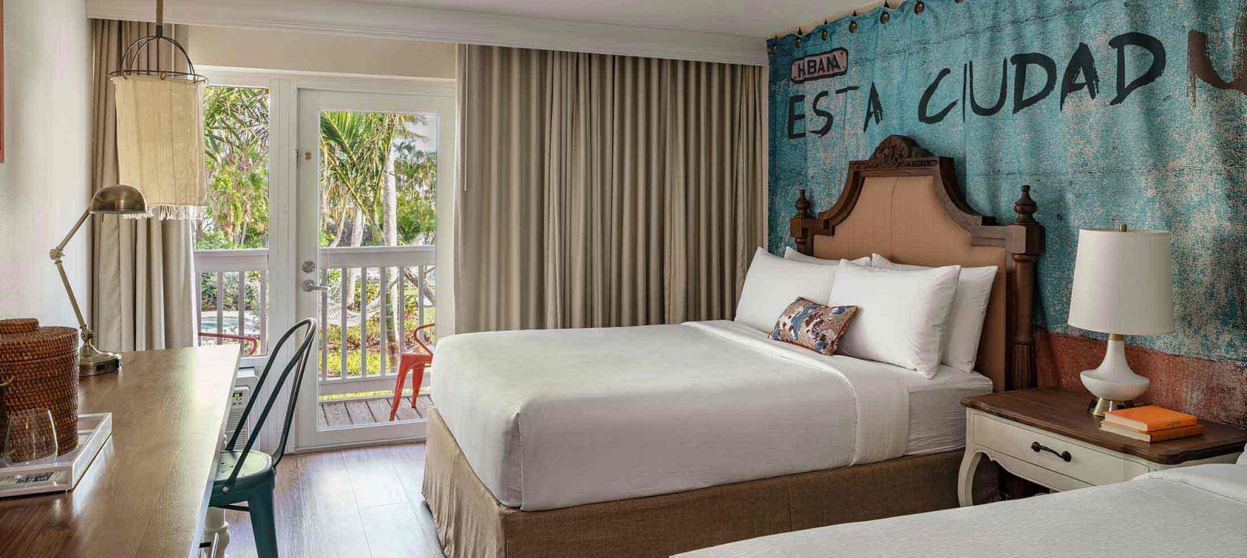 Twin queen-sized beds with a bedside table in between overlooking a desk