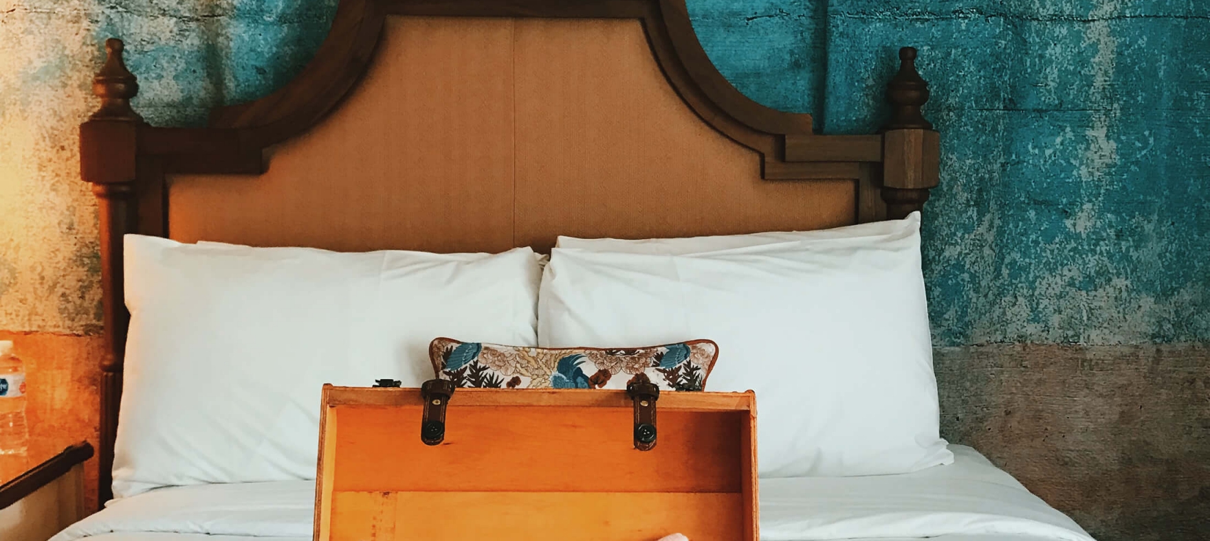 A vertical shot of opened luggage on a bed containing a cell phone, bikini, sandals, and more placed on a bed at a Havana Cabana room