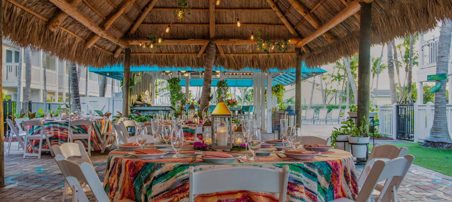 Tiki Hut table decor with plates, cutleries and glasses placed on a multi-colored table cloth
