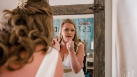 A rear view of a bride looking at the mirror and applying lip gloss