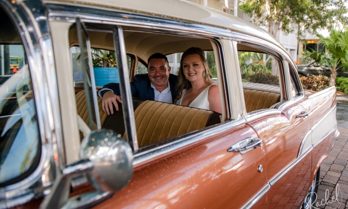 A man and woman smile and sit in the back of a 1957 Chevrolet Bel Air 4-door Sedan.