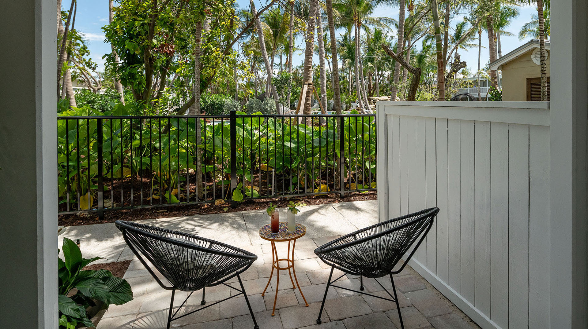 A ground floor balcony at Havana Cabana resort equipped with two black chairs and a small wicker table.