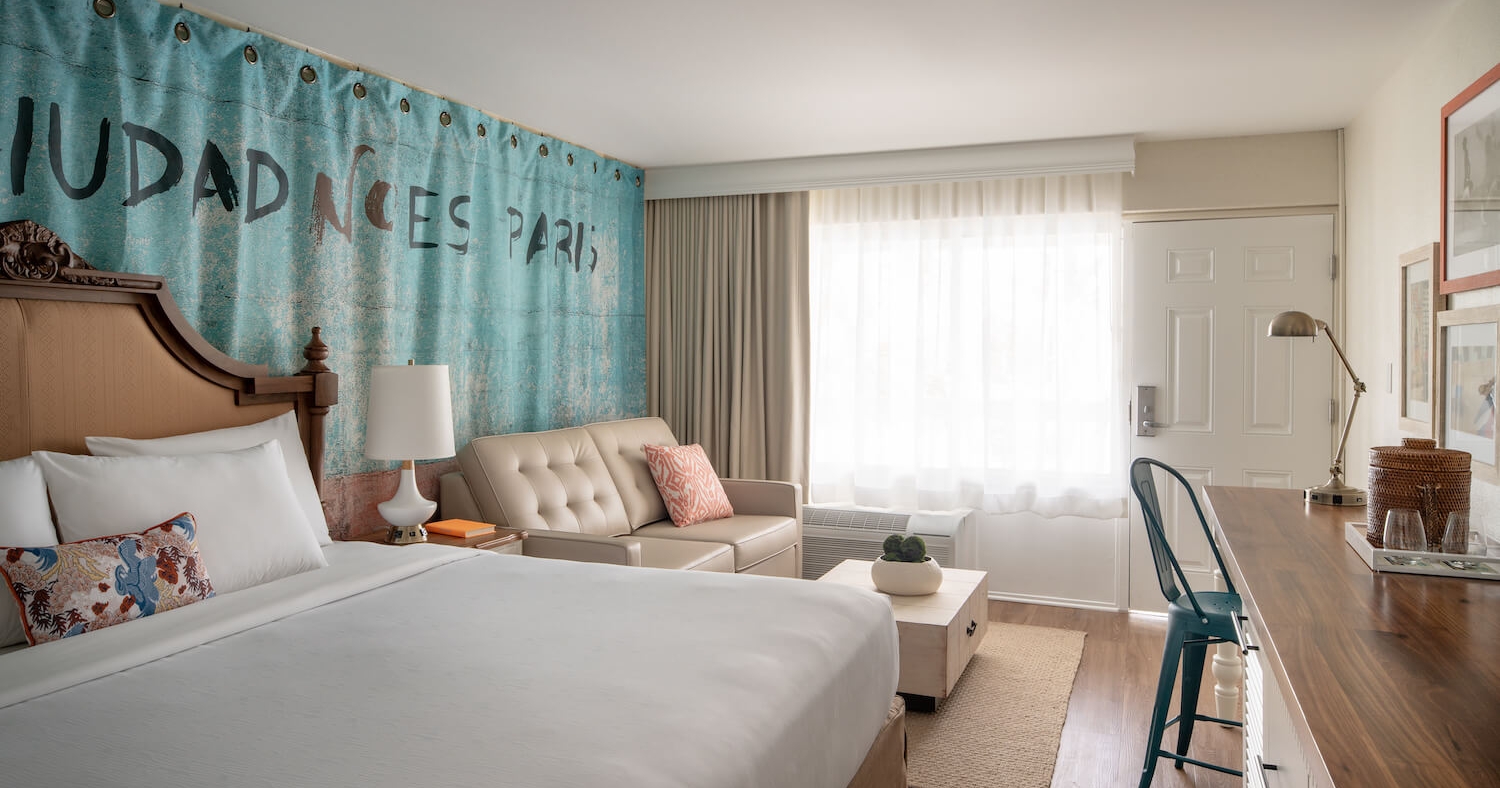 A king bed, couch and long wooden table found in an accessible room at Havana Cabana resort.