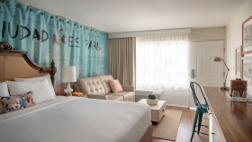 A king bed, couch and long wooden table found in an accessible room at Havana Cabana resort.