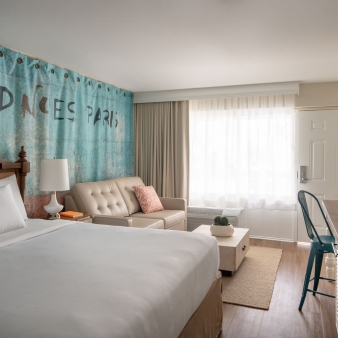 A king bed, couch and long wooden table found in an accessible room at Havana Cabana resort.