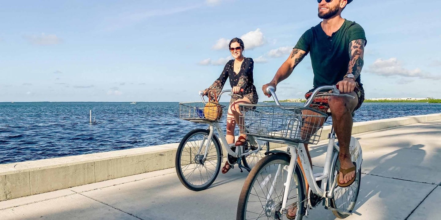 A man and a woman biking next to the water.