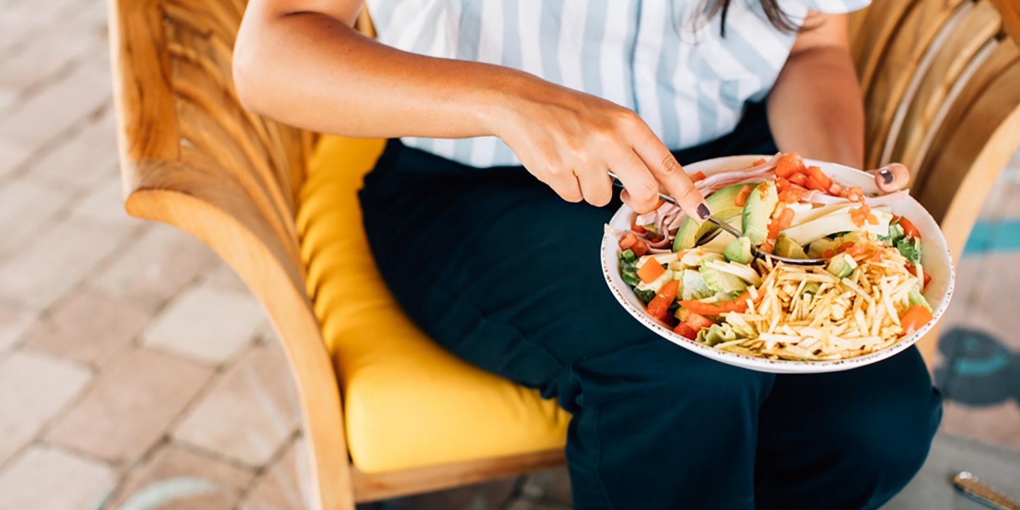 Woman sitting with an avocado and taco salad plate in her lap