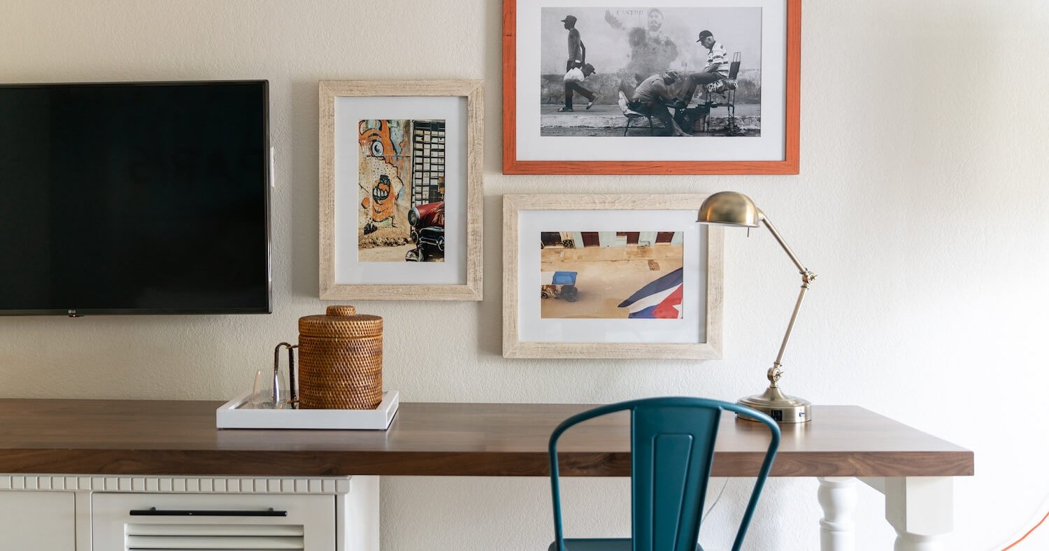 Three colorful photos hung on a white wall above a desk.