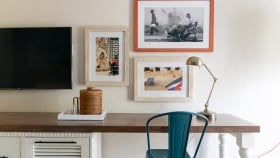 Three colorful photos hung on a white wall above a desk.