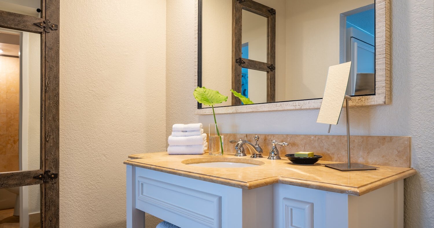 A white and marble bathroom with a large mirror.