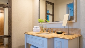 A white and marble bathroom with a large mirror.