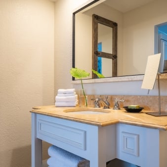 A white and marble bathroom with a large mirror.