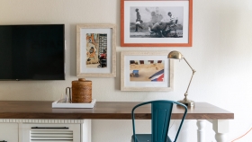 A wooden table, equipped with a metal blue chair and a gold desk lamp.