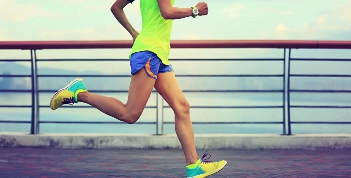 Woman running on a boardwalk in colourful running gear